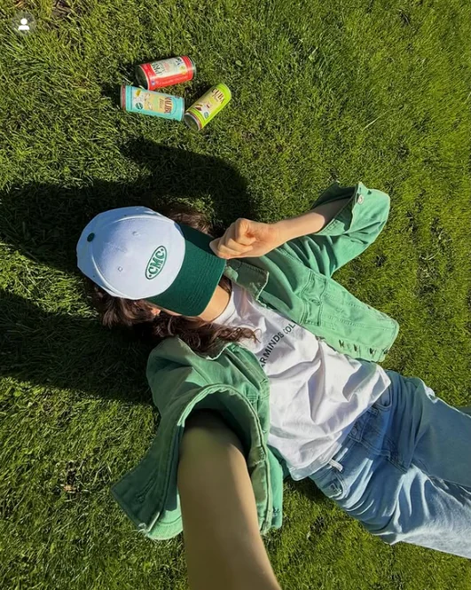 A person lying on grass surrounded by Good Spirits cans